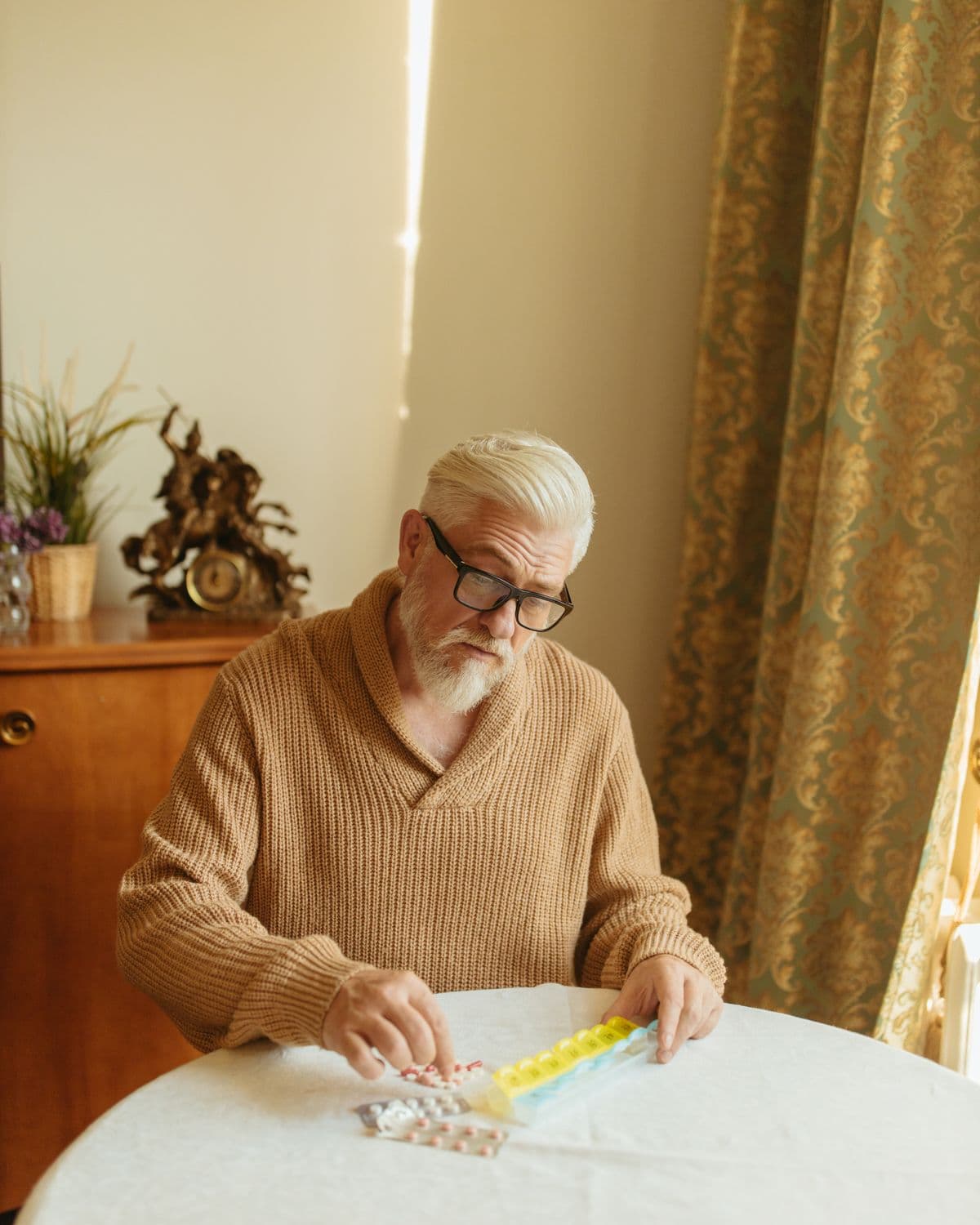 An older man organising his medication at home